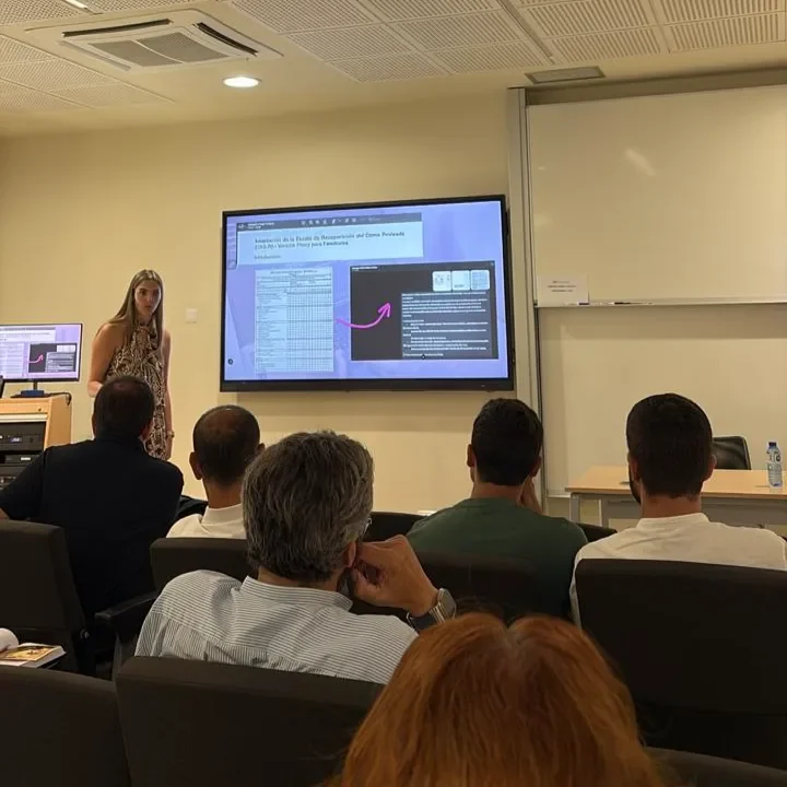 Una ponente explicando una escala clínica proyectada en pantalla ante una sala de profesionales sentados